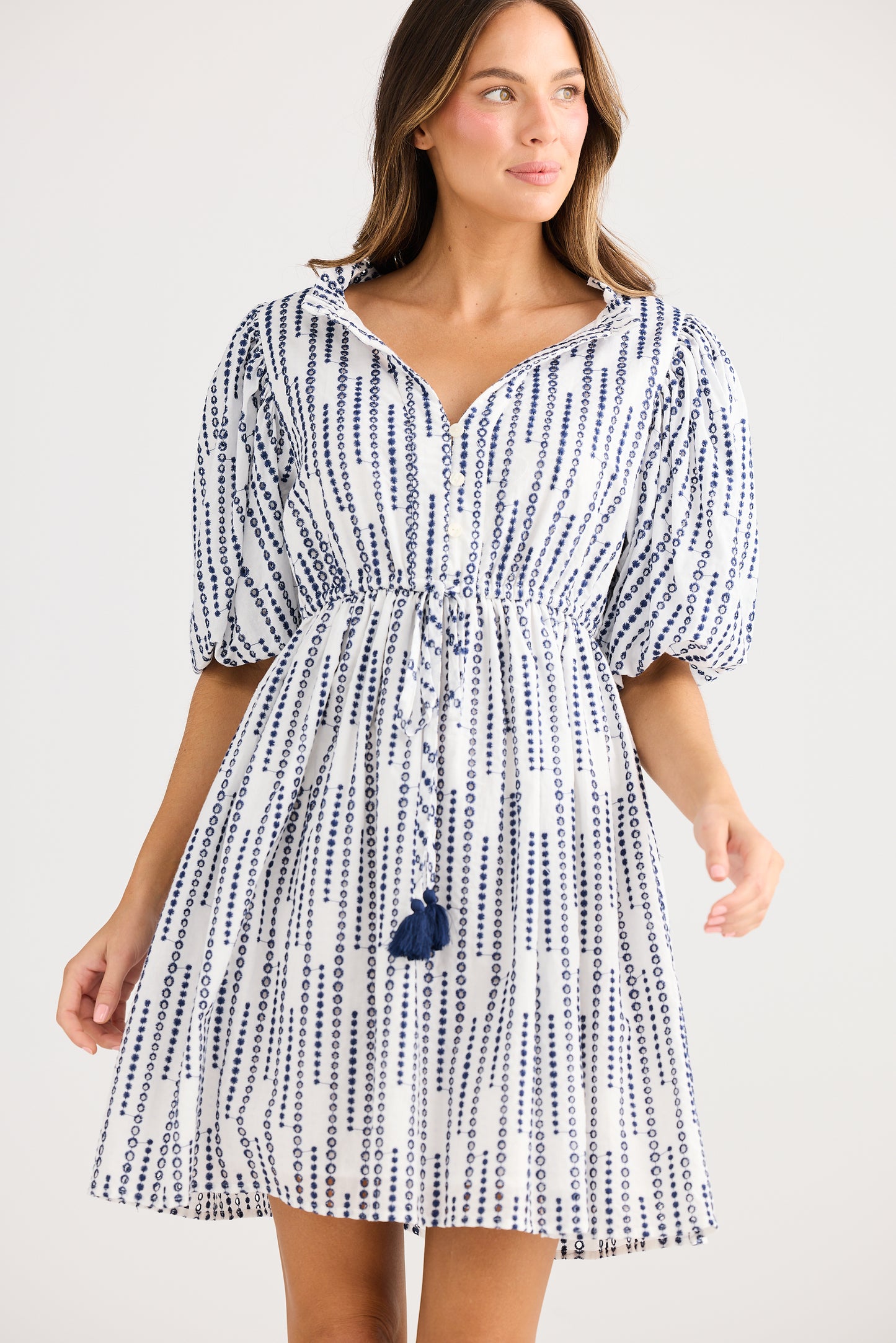 Woman wearing a blue and white patterned dress on a plain background