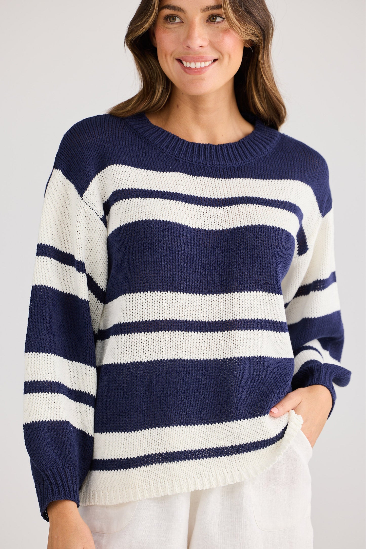 Woman wearing a navy and white striped sweater against a plain background