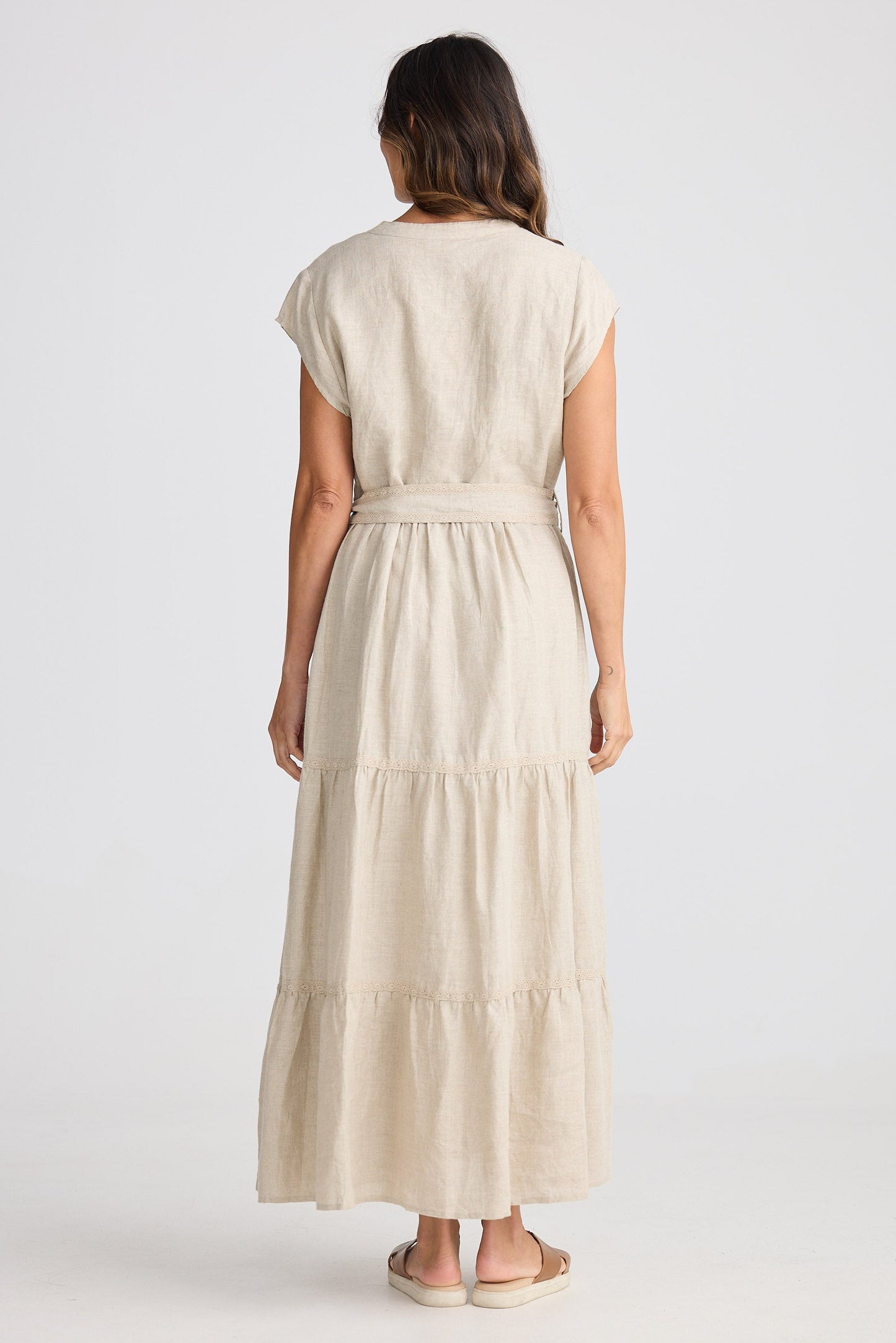Woman wearing a beige dress with a belt on a white background
