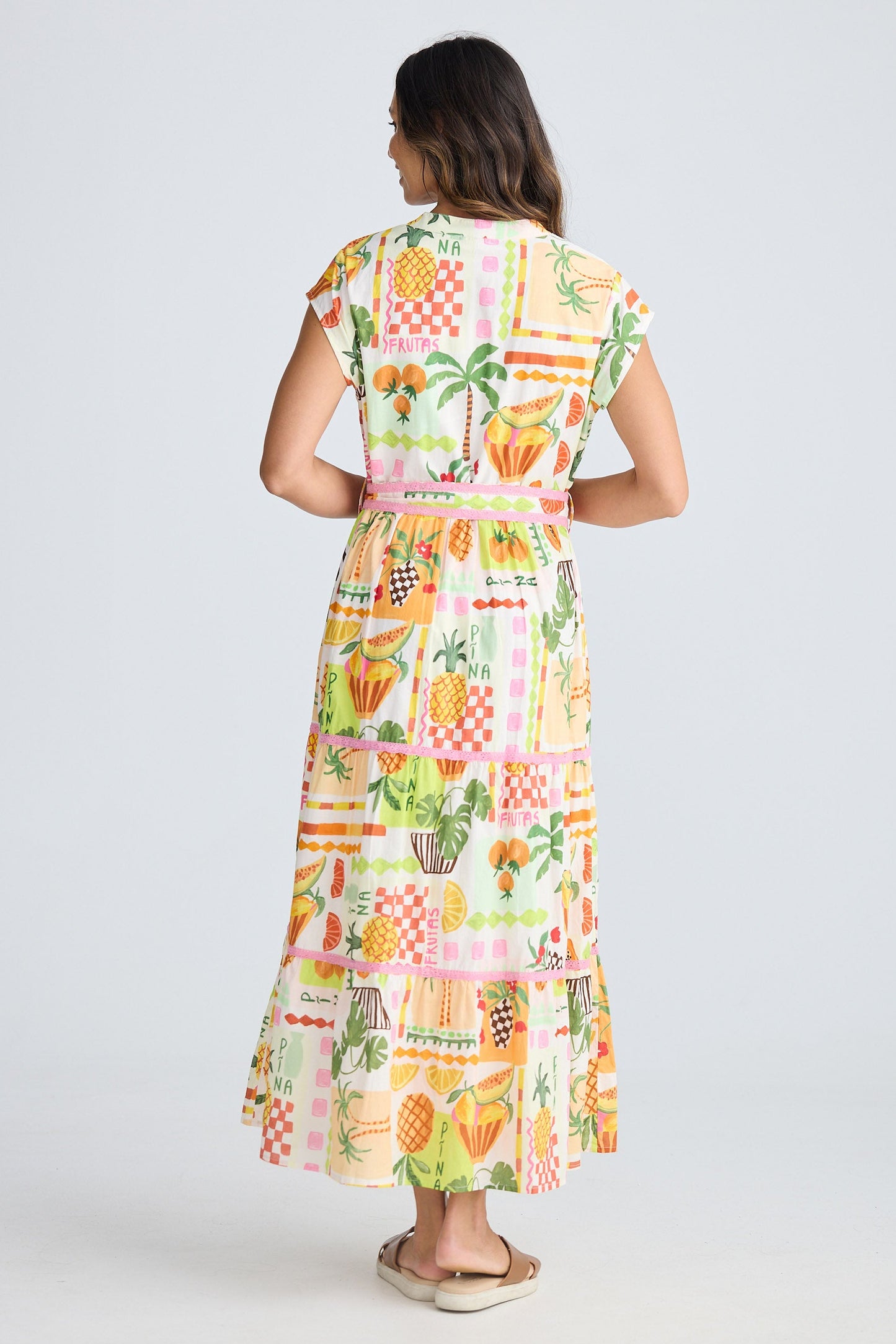 Woman wearing a colorful dress with a fruit pattern on a white background