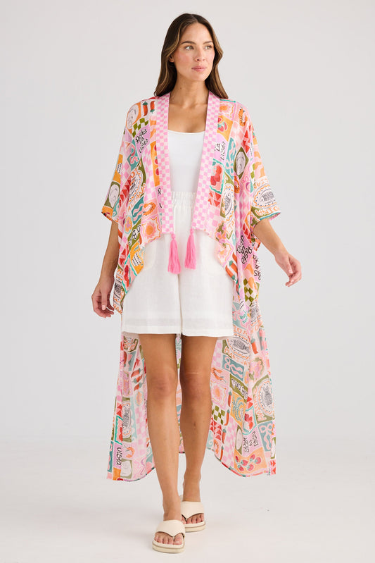 Woman wearing a colorful kimono-style jacket over a white dress on a light gray background