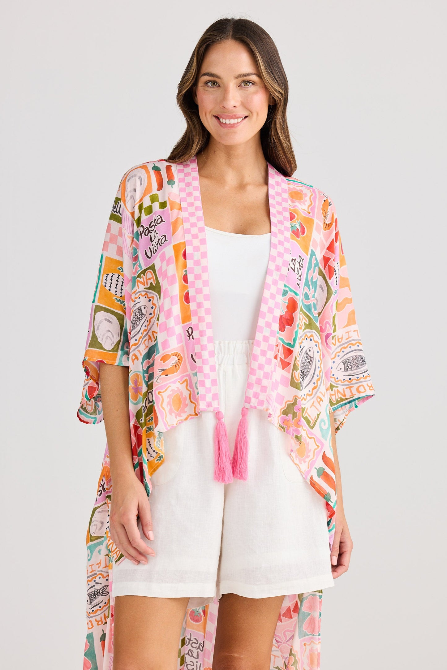 Woman wearing a colorful kimono-style jacket over a white dress on a light gray background