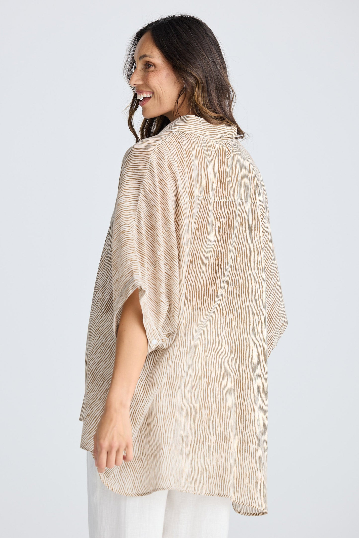 Woman wearing a beige textured shirt against a white background