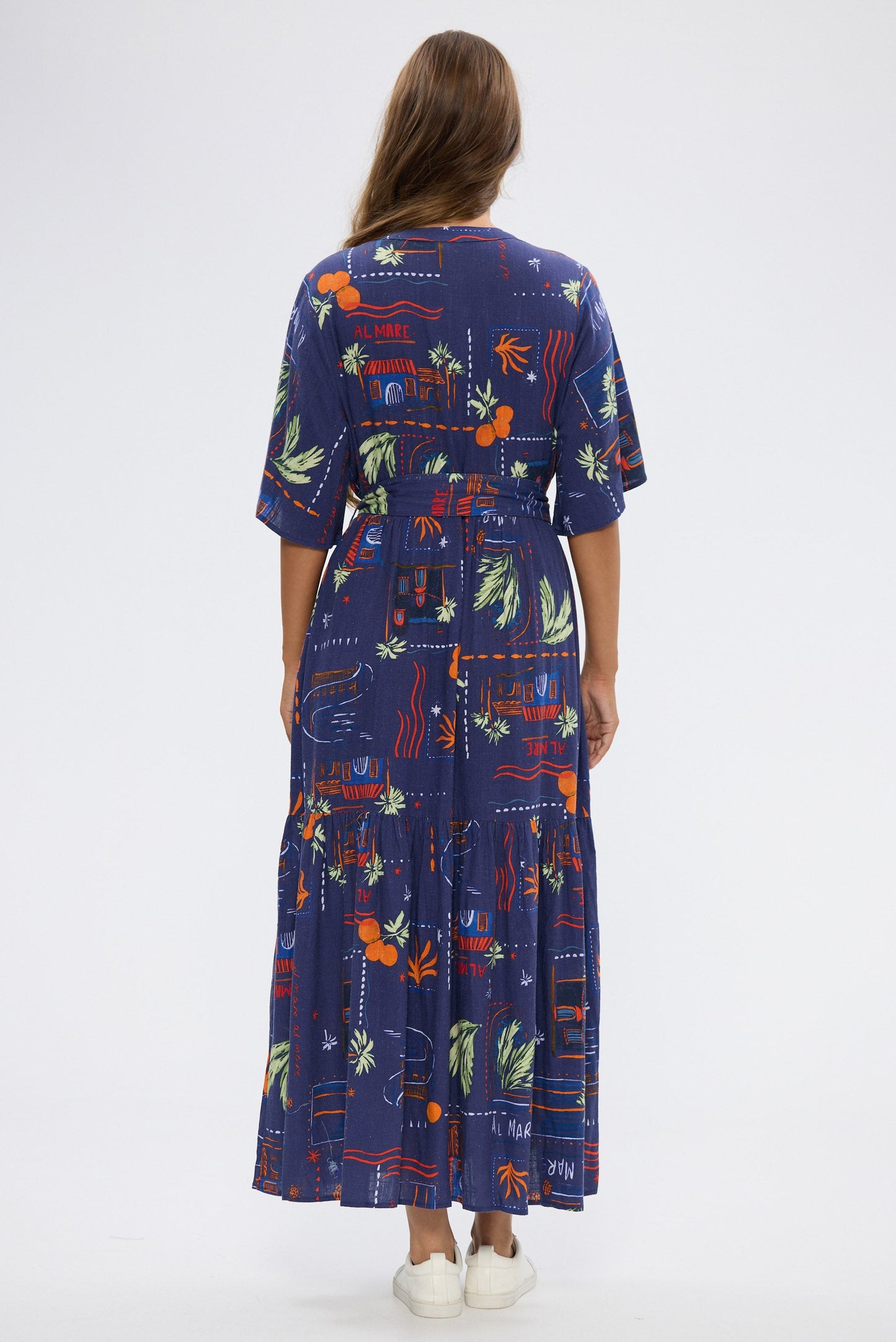 Woman wearing a long, dark blue dress with colorful geometric pattern on a white background