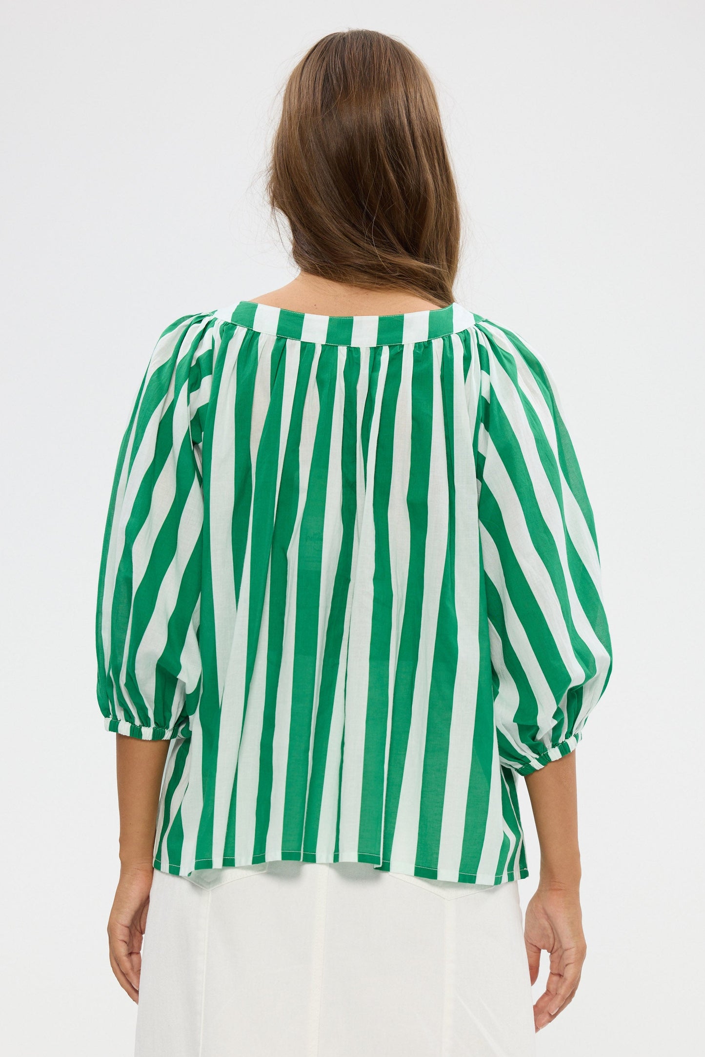 Woman wearing a green and white striped blouse against a white background