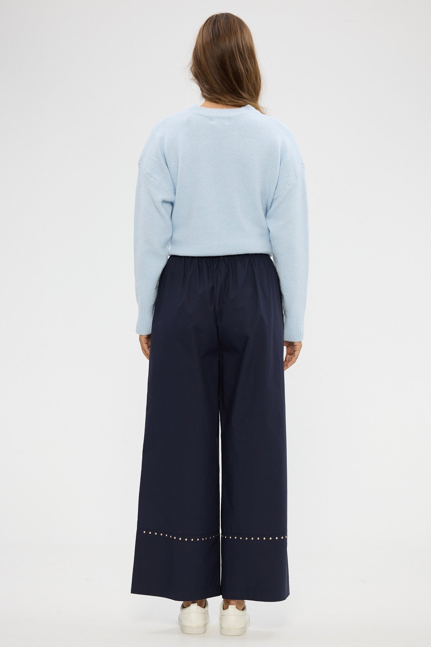 Person wearing a light blue sweater and dark blue pants on a white background