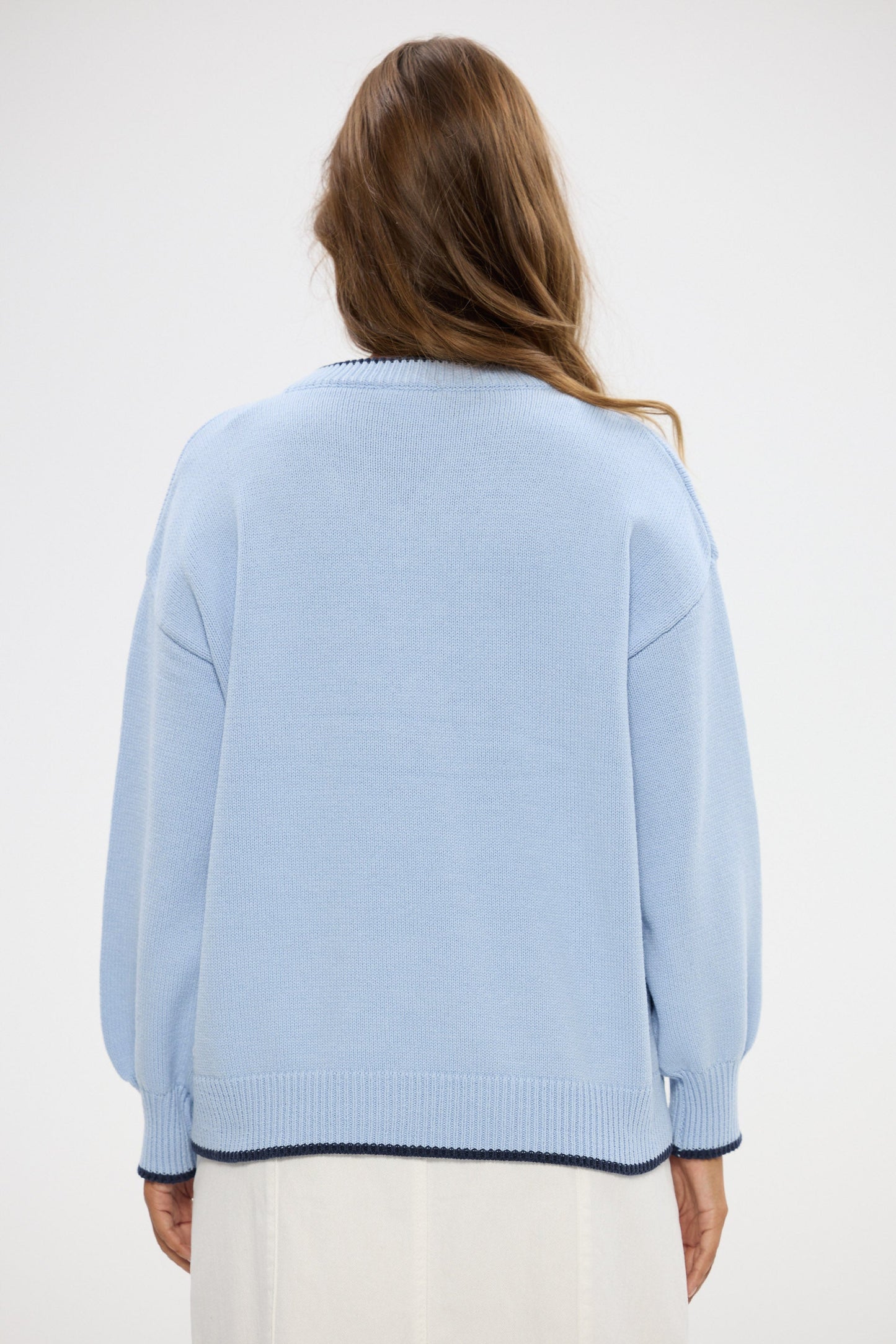 Person wearing a light blue sweater with a white background