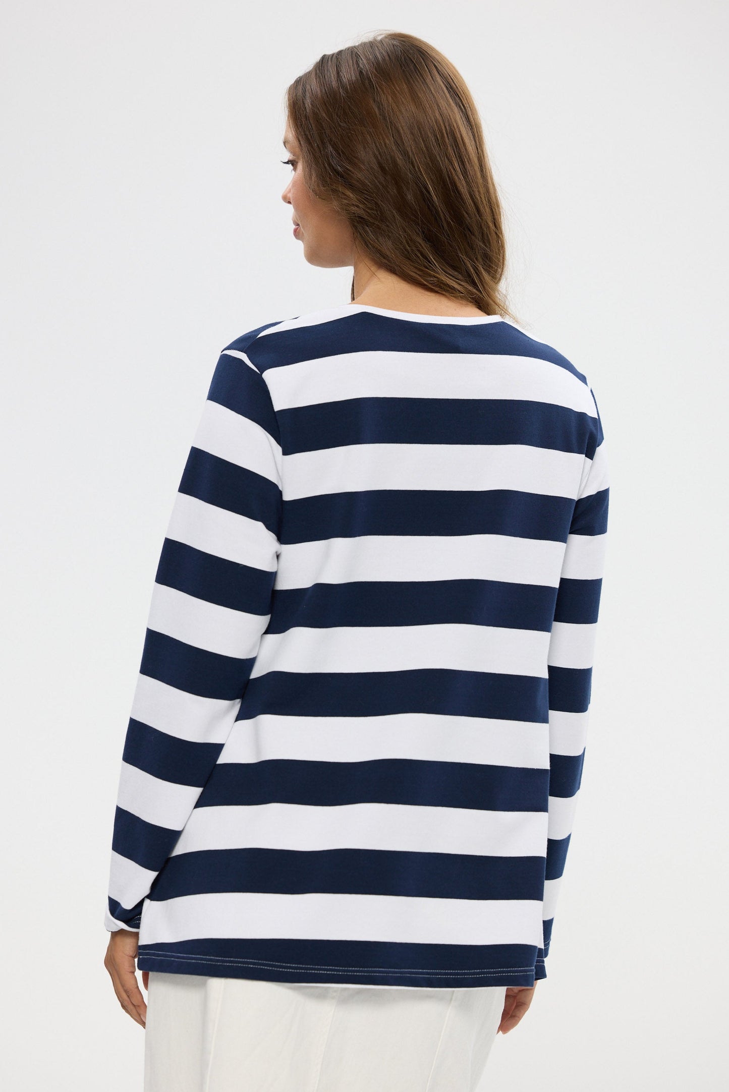Woman wearing a navy and white striped long-sleeve shirt on a plain background