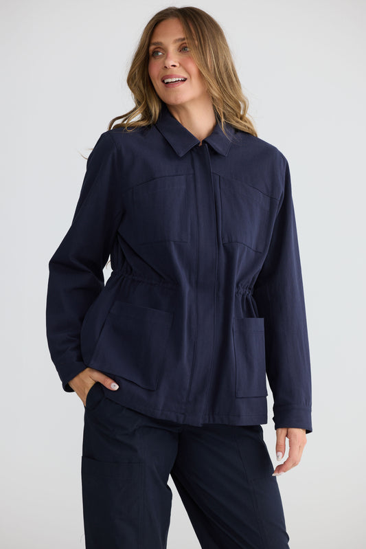Model wearing Sabbia Jacket Navy with concealed zip and waist drawcord, front view on white background