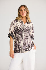 Model wearing Playa Shirt in sunset palm, front view. Relaxed short sleeve, button front, black-and-cream palm-leaf print.