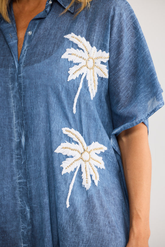 Model wearing Halia Shirt Kaftan in navy, front view. Wide dolman sleeve, button front, palm embroidery at shoulders and hem.