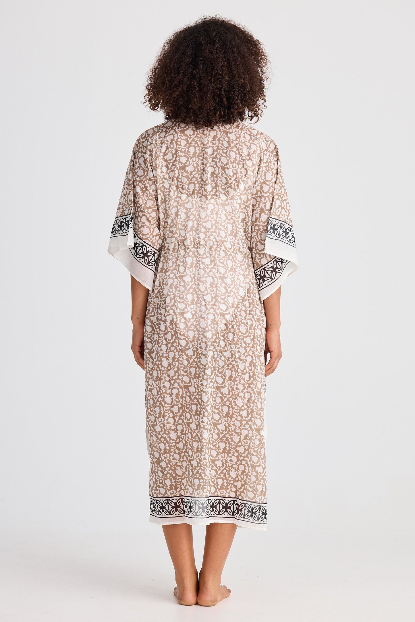 Woman wearing a patterned kaftan with a plain background