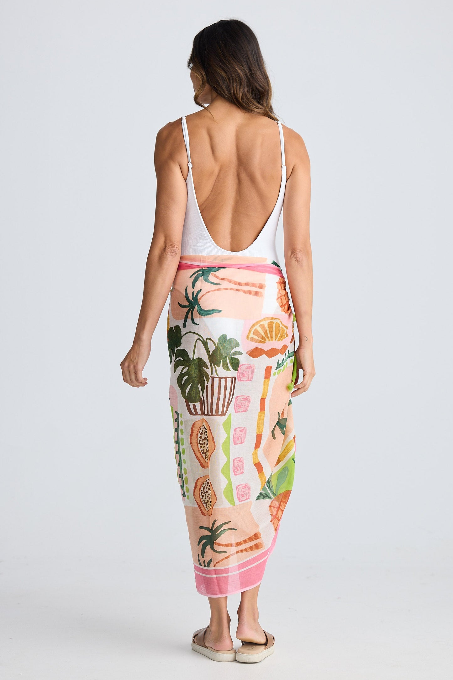 Woman wearing a colorful sarong with tropical patterns on a white background