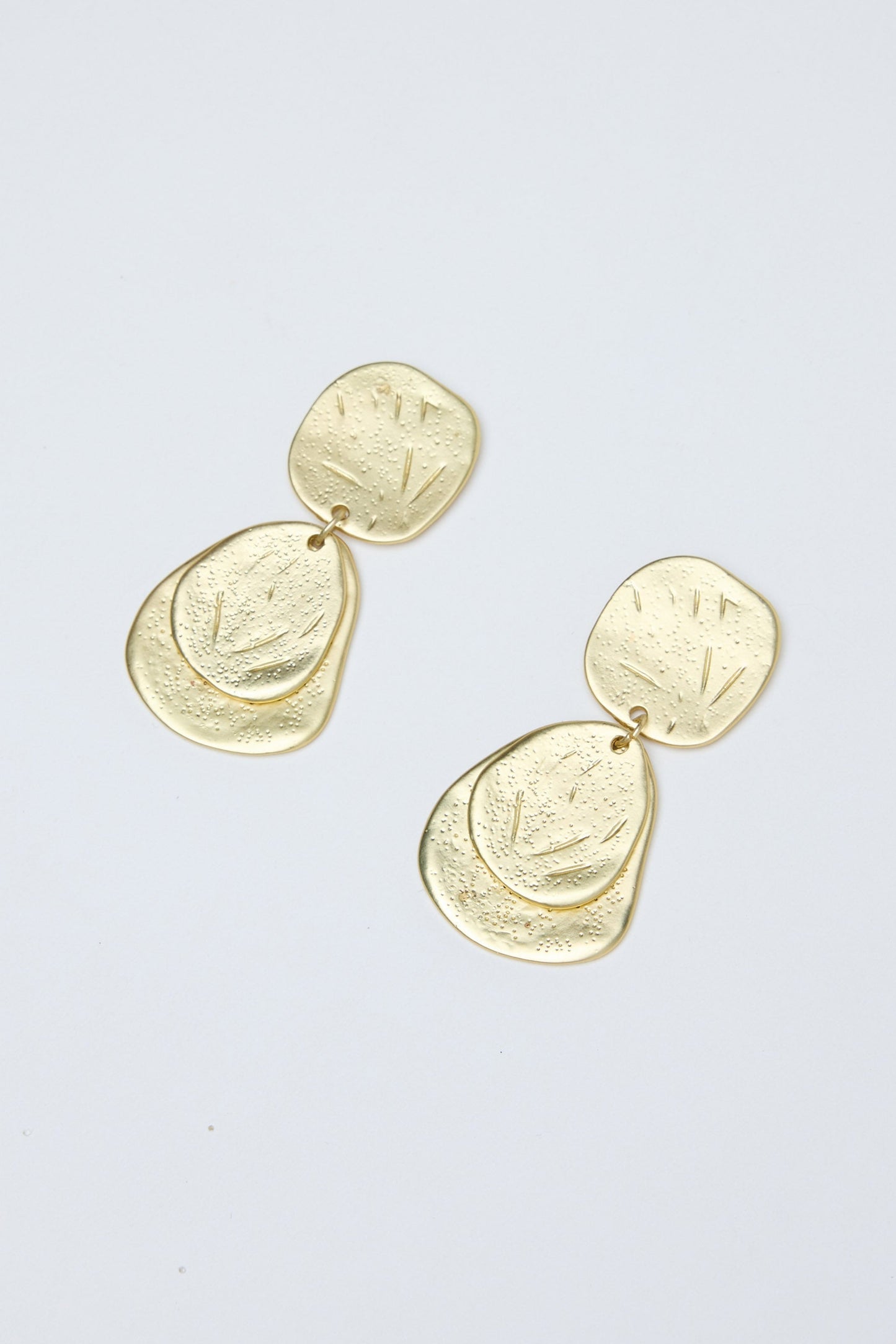 Gold earrings on a light gray background