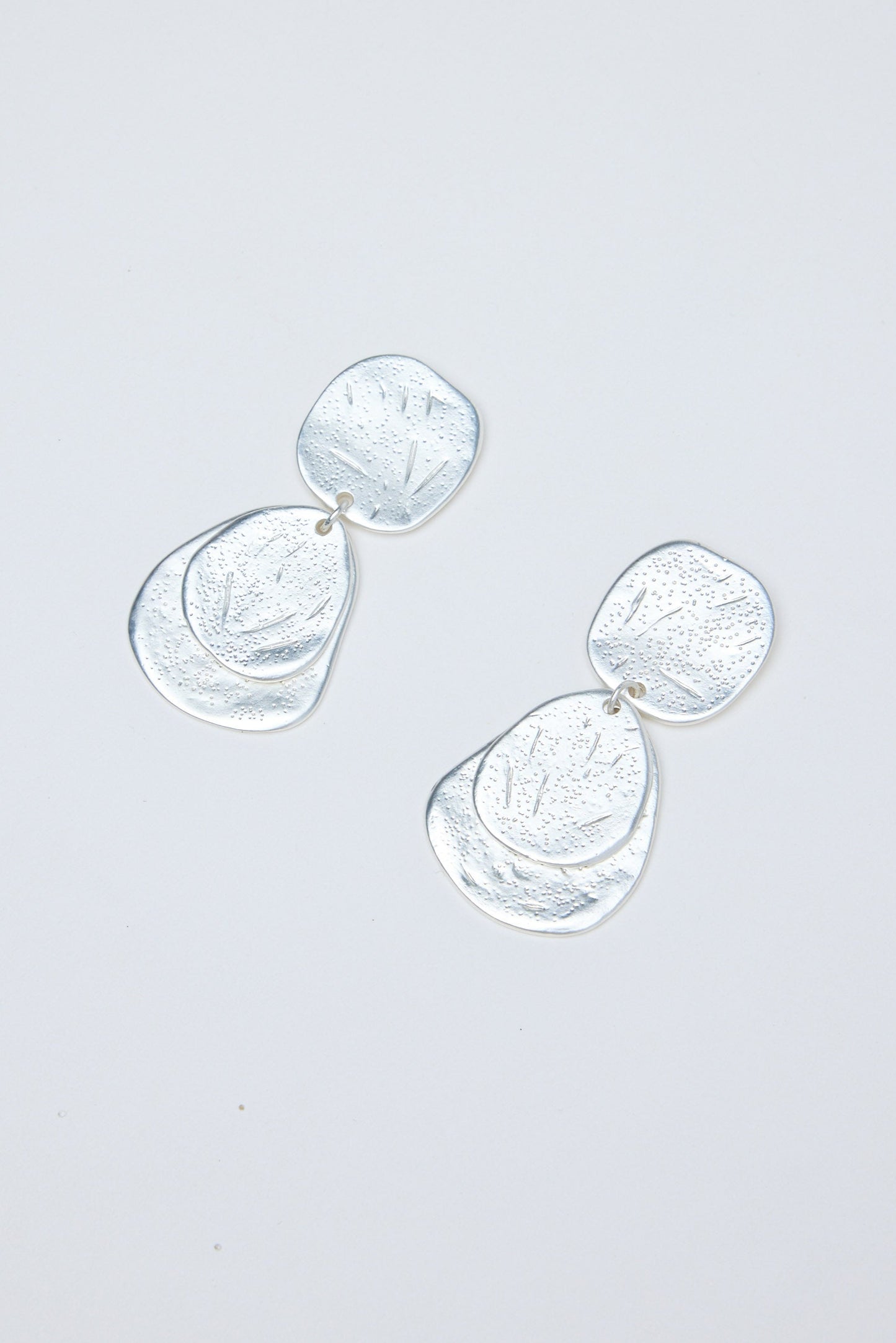 Silver earrings on a light gray background