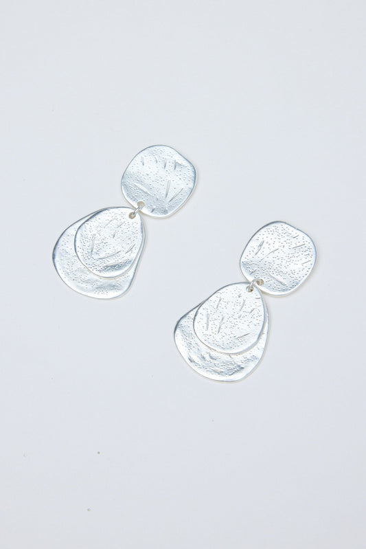 Silver earrings on a light gray background