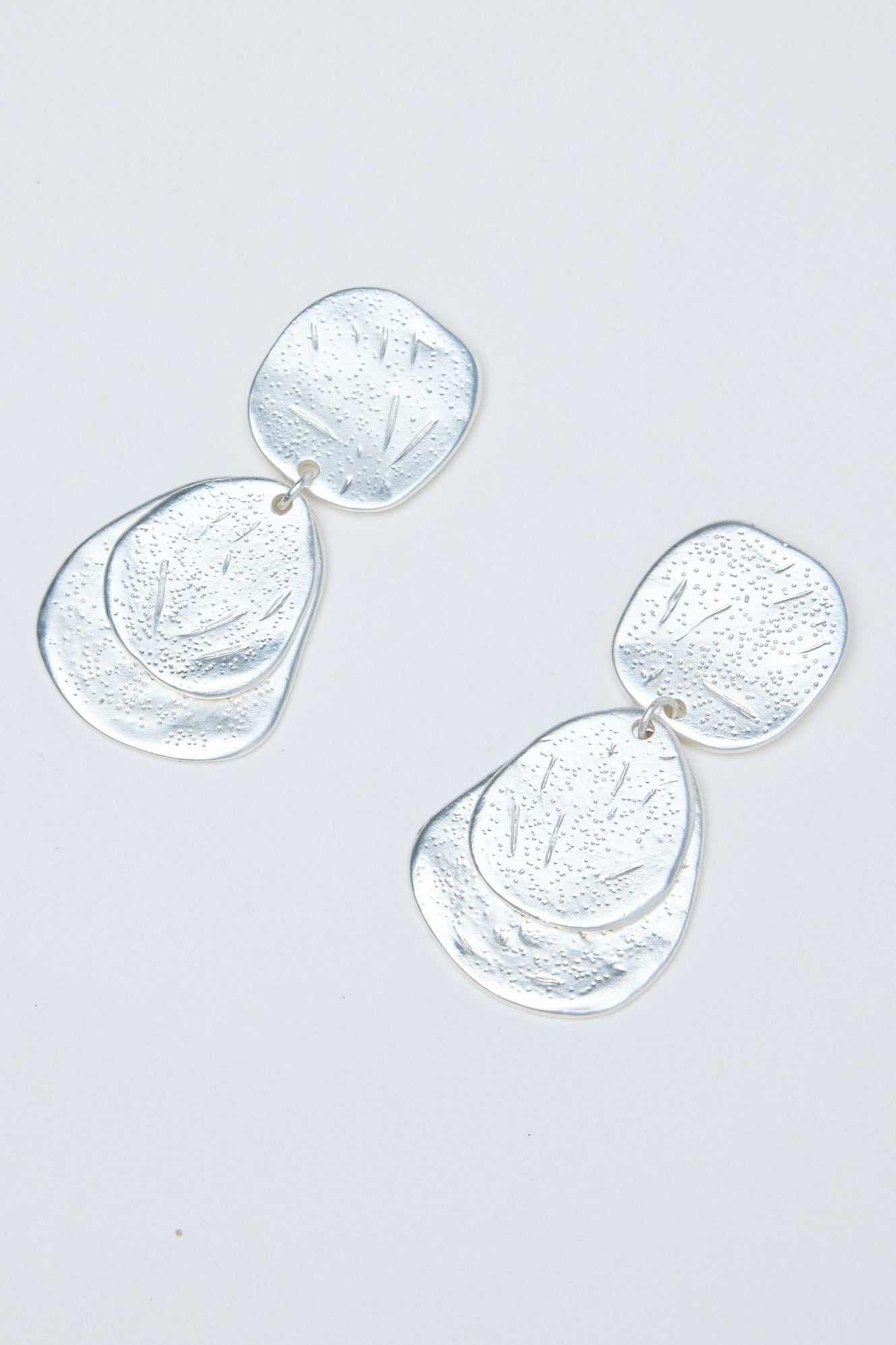 Silver earrings on a light gray background