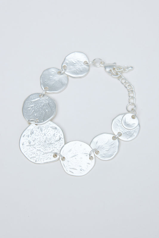 Silver bracelet with round, textured discs on a light gray background