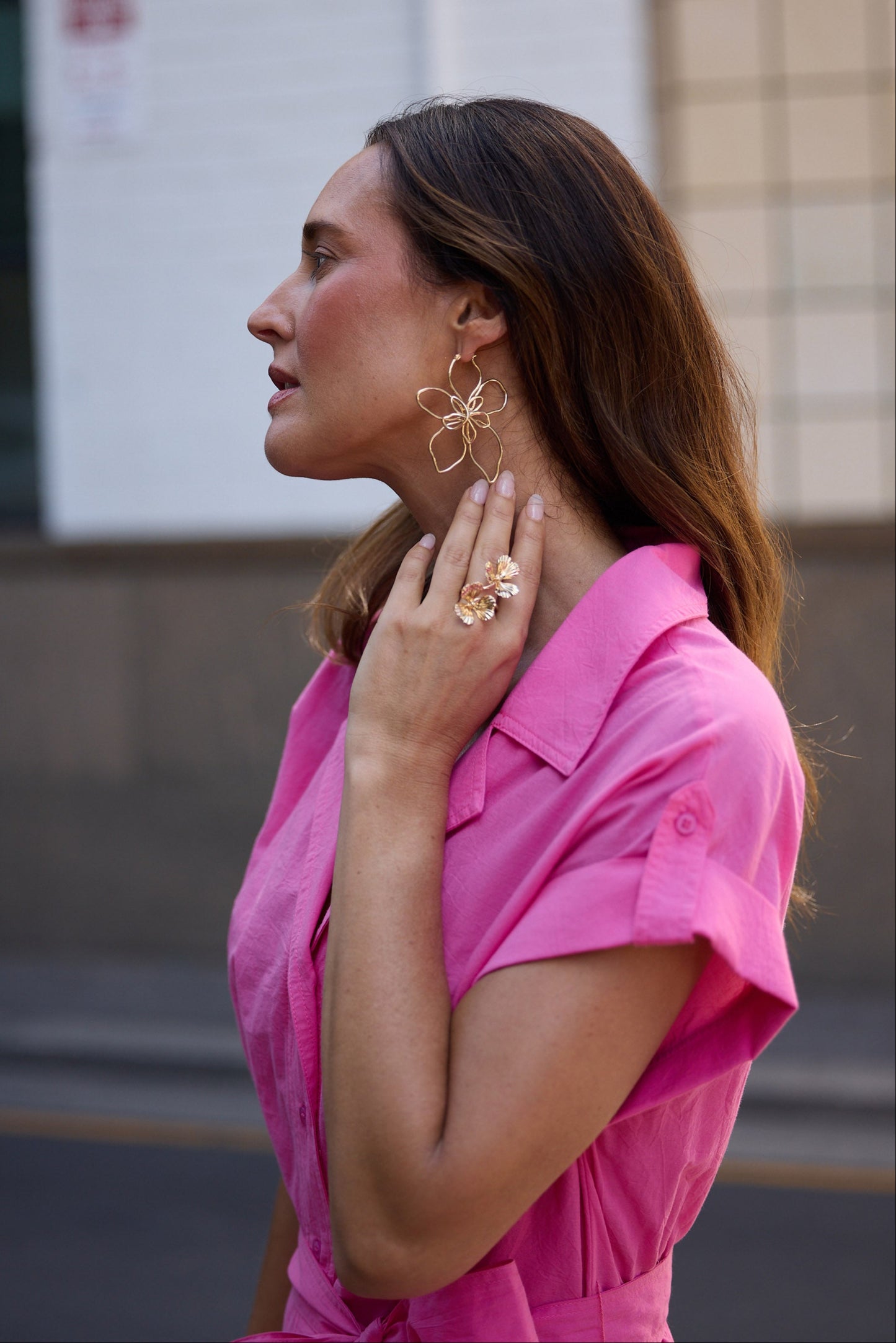 Woman wearing a pink shirt and gold jewelry outdoors