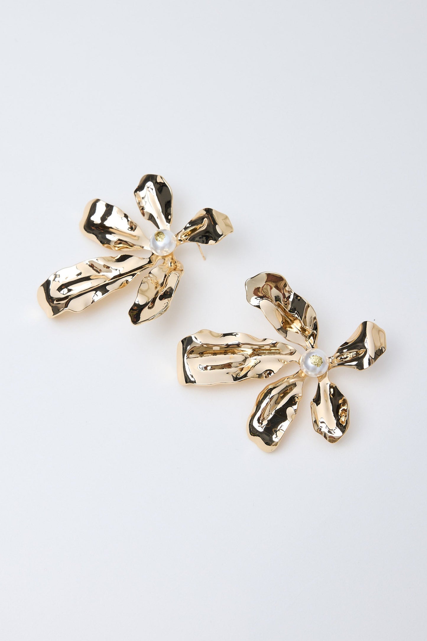 Gold flower-shaped earrings on a light gray background