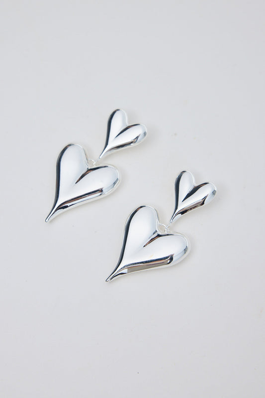 Silver heart-shaped earrings on a light gray background