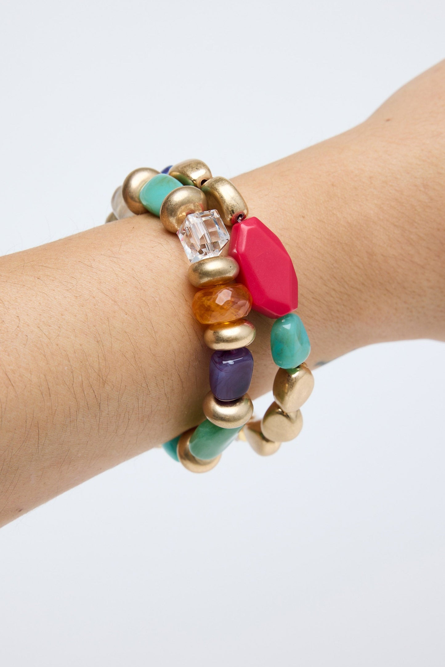 Multicolored beaded bracelet on a wrist against a white background