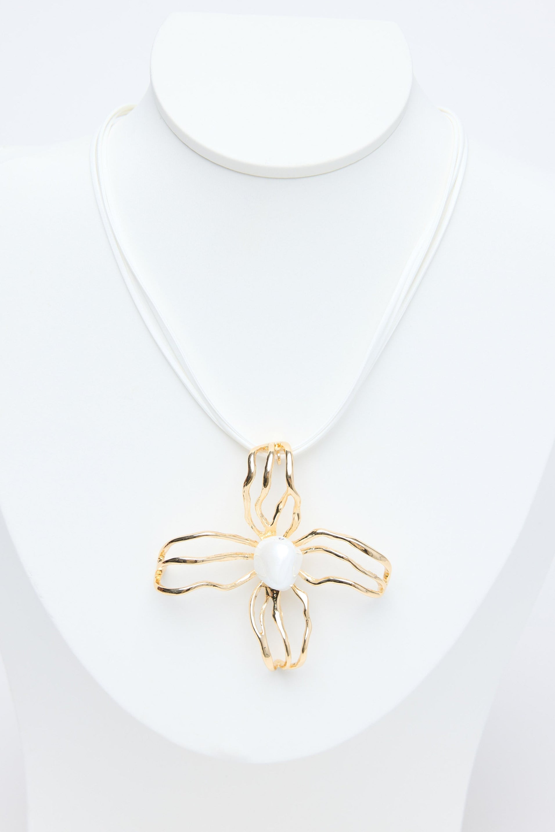 Gold flower pendant on a white necklace against a white background