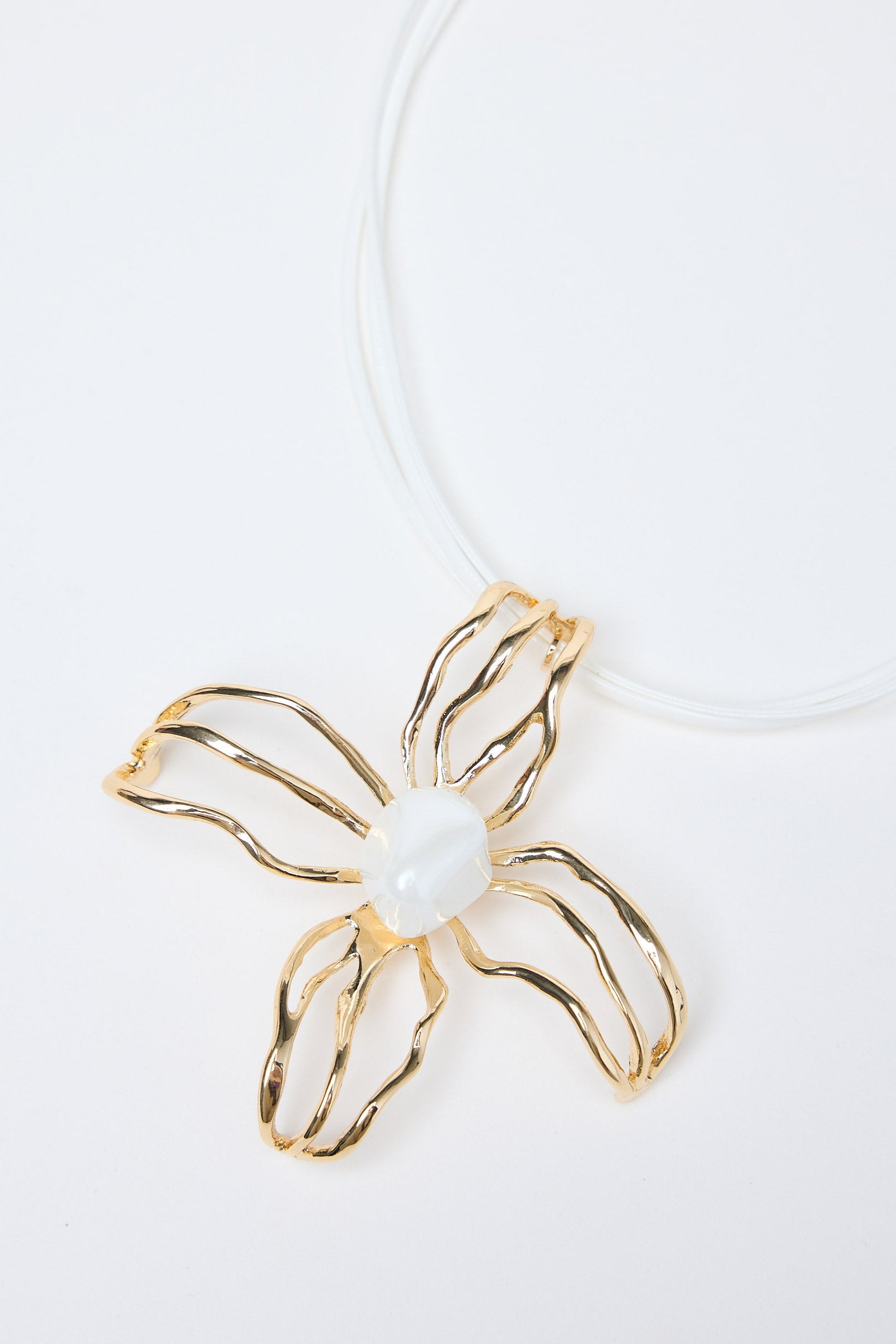 Gold flower-shaped pendant with a pearl on a white background