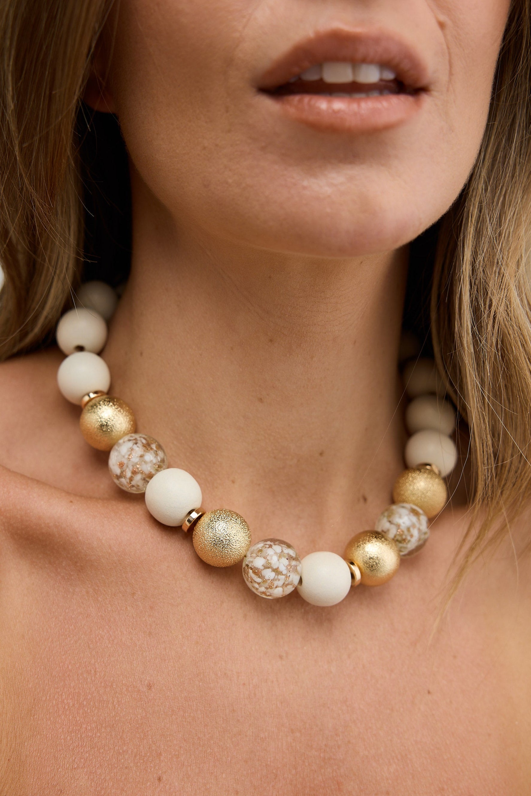 Close-up of a woman wearing a beaded necklace with a blurred background