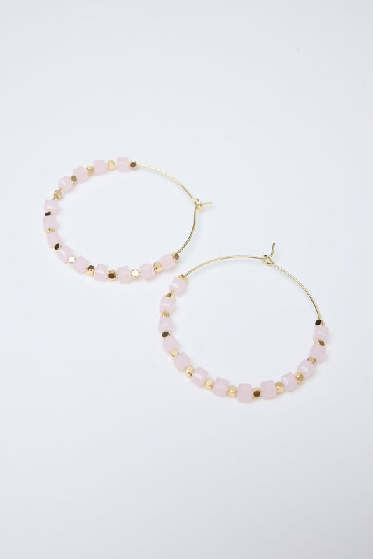 Pair of gold hoop earrings with small light pink beads on a white background