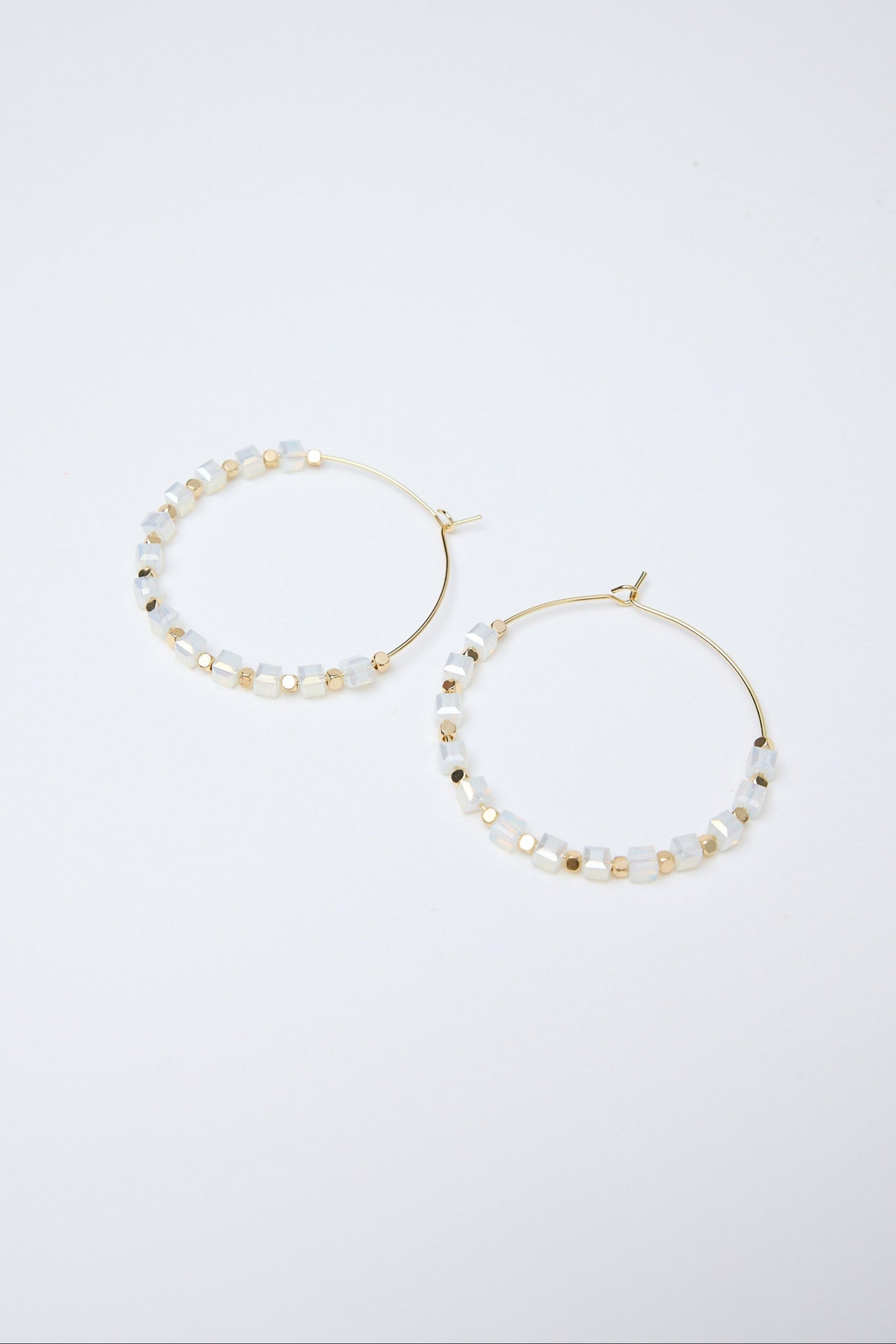 Pair of hoop earrings with pearl-like beads on a white background
