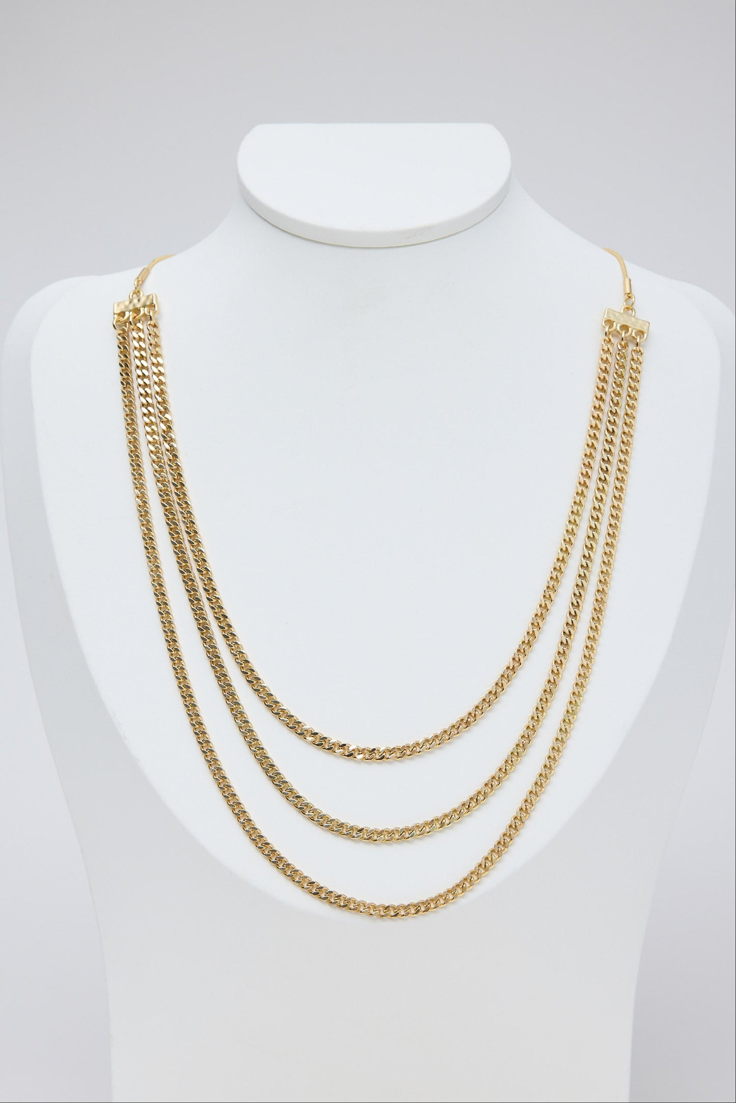 Gold chain necklace on a mannequin bust against a white background