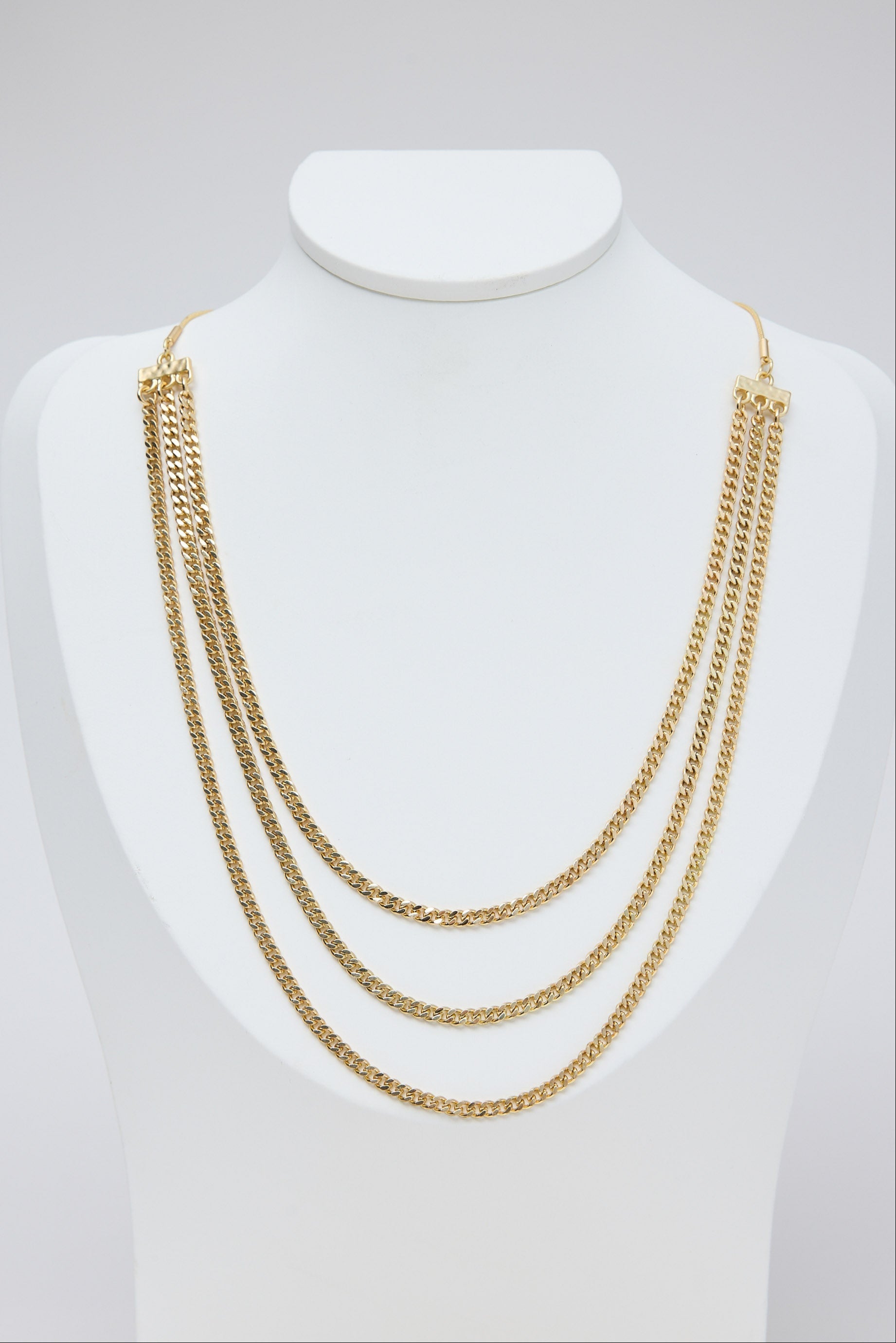 Gold chain necklace on a mannequin bust against a white background