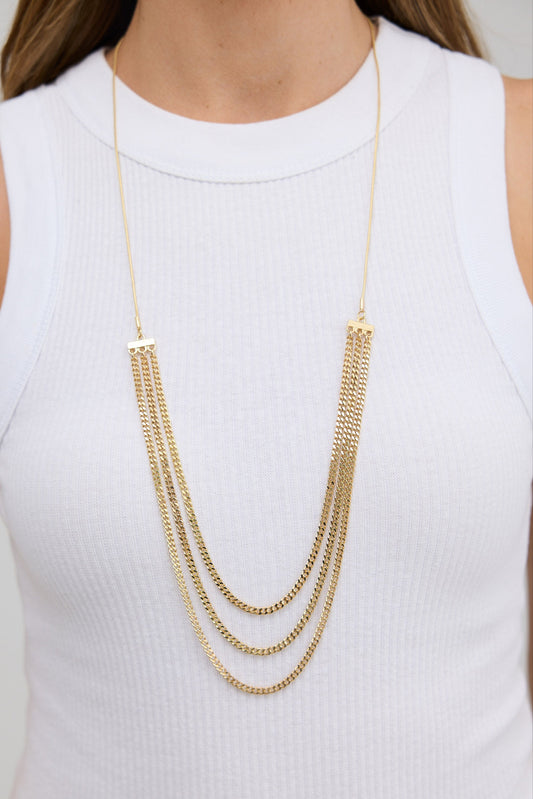 Gold chain necklace worn by a person on a white background