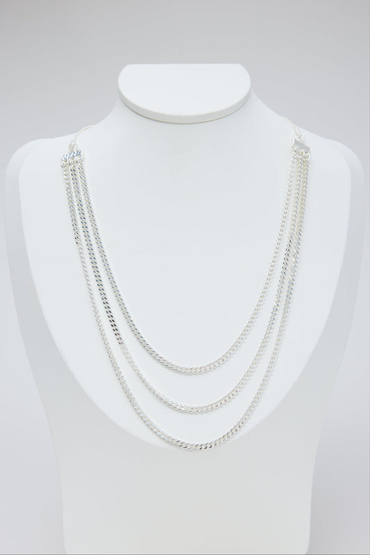 Set of silver necklaces on a mannequin bust against a light gray background
