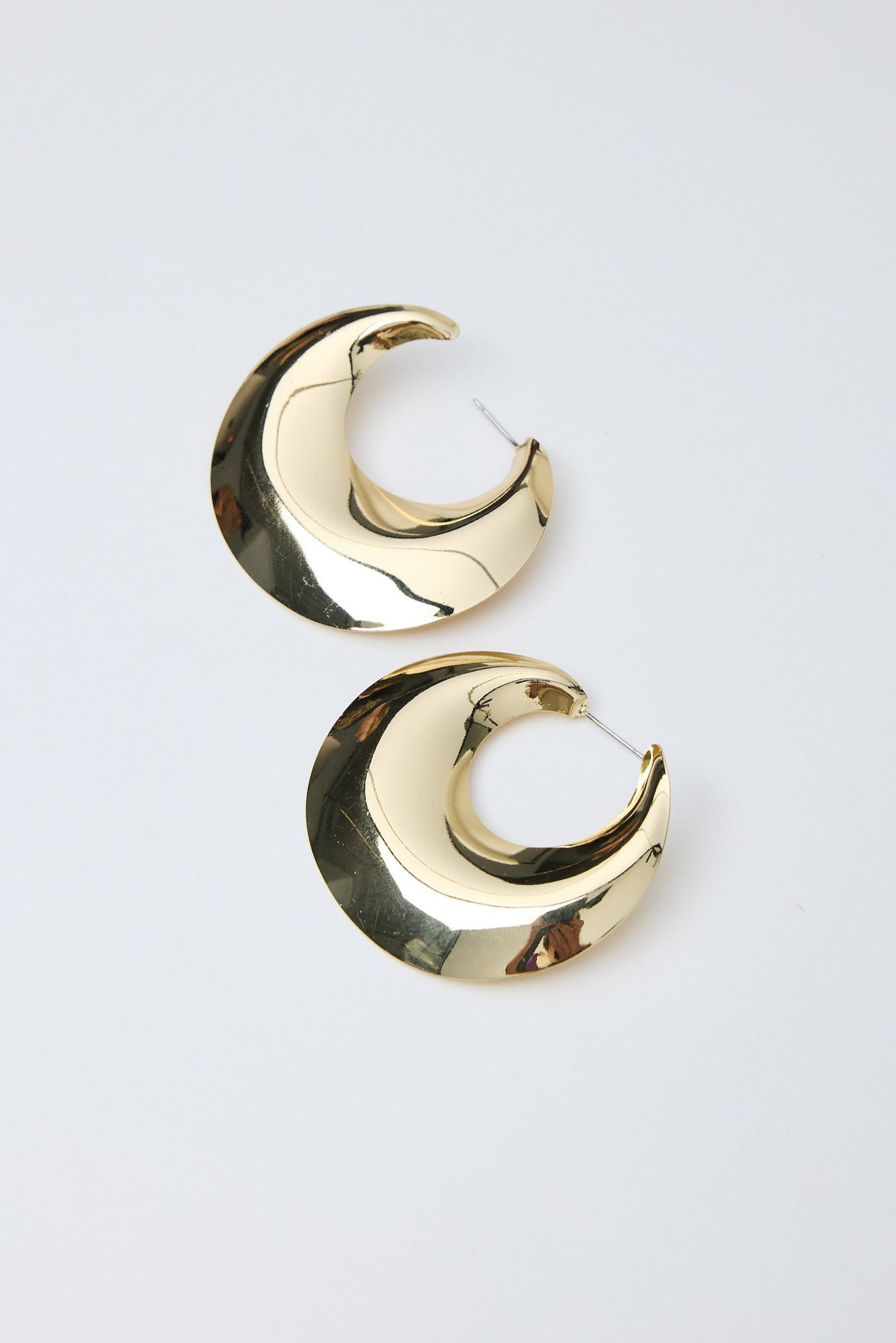 Gold crescent moon earrings on a light gray background