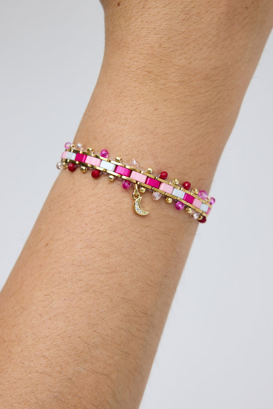 Bracelet with pink and red beads on a wrist against a light gray background