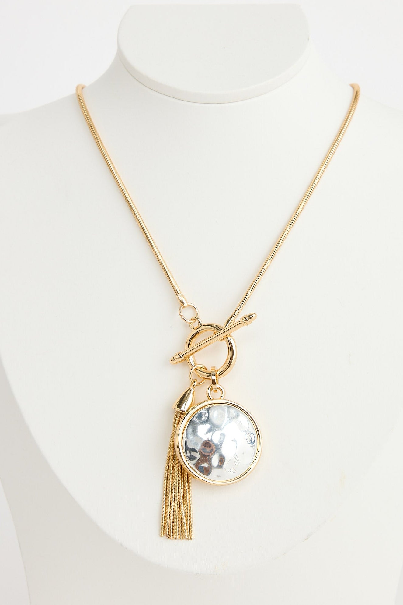 Gold necklace with a pendant on a mannequin against a white background