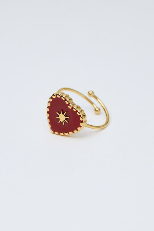 Gold ring with a red heart-shaped stone on a white background