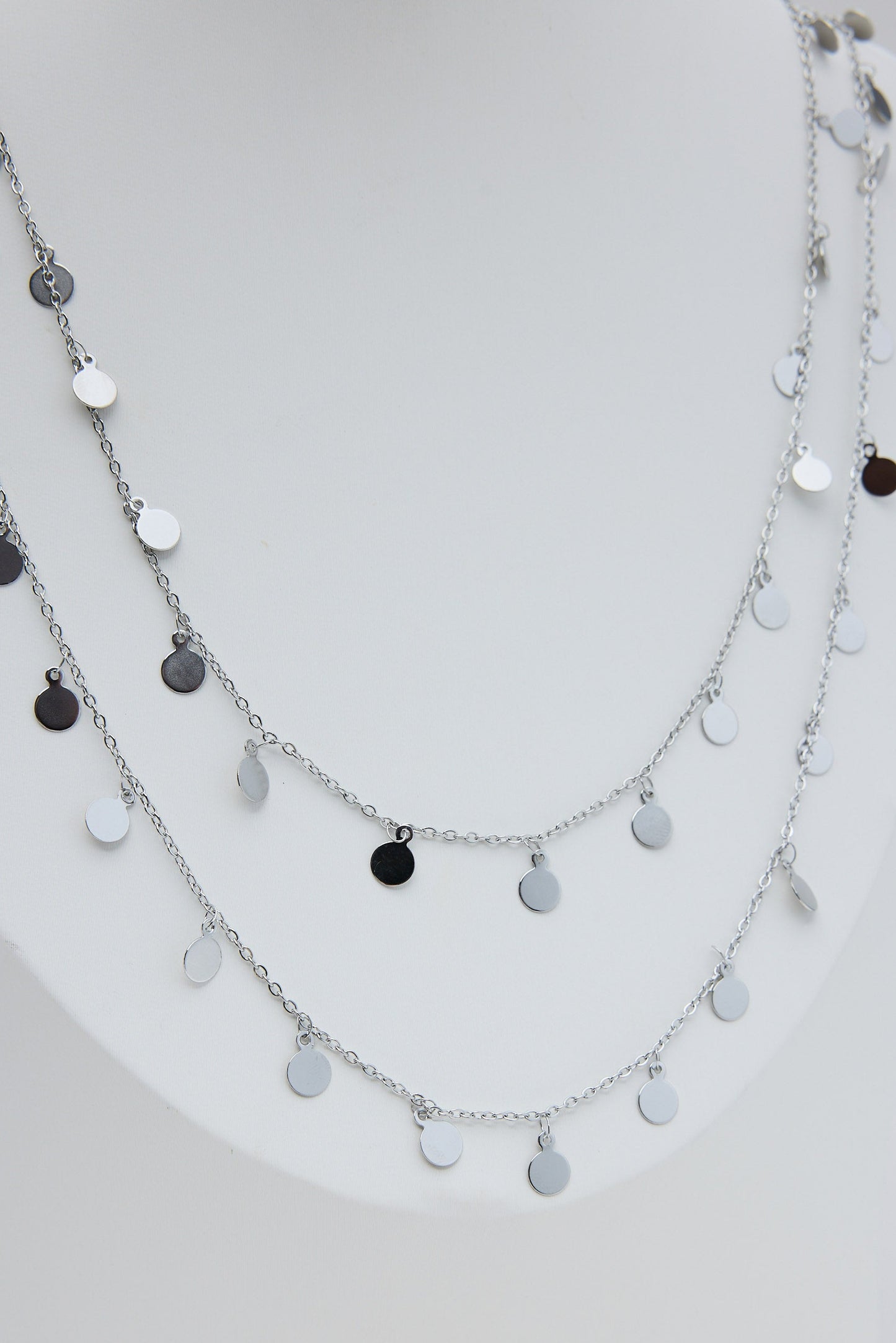 Layered silver necklace with black and white pendants on a white background