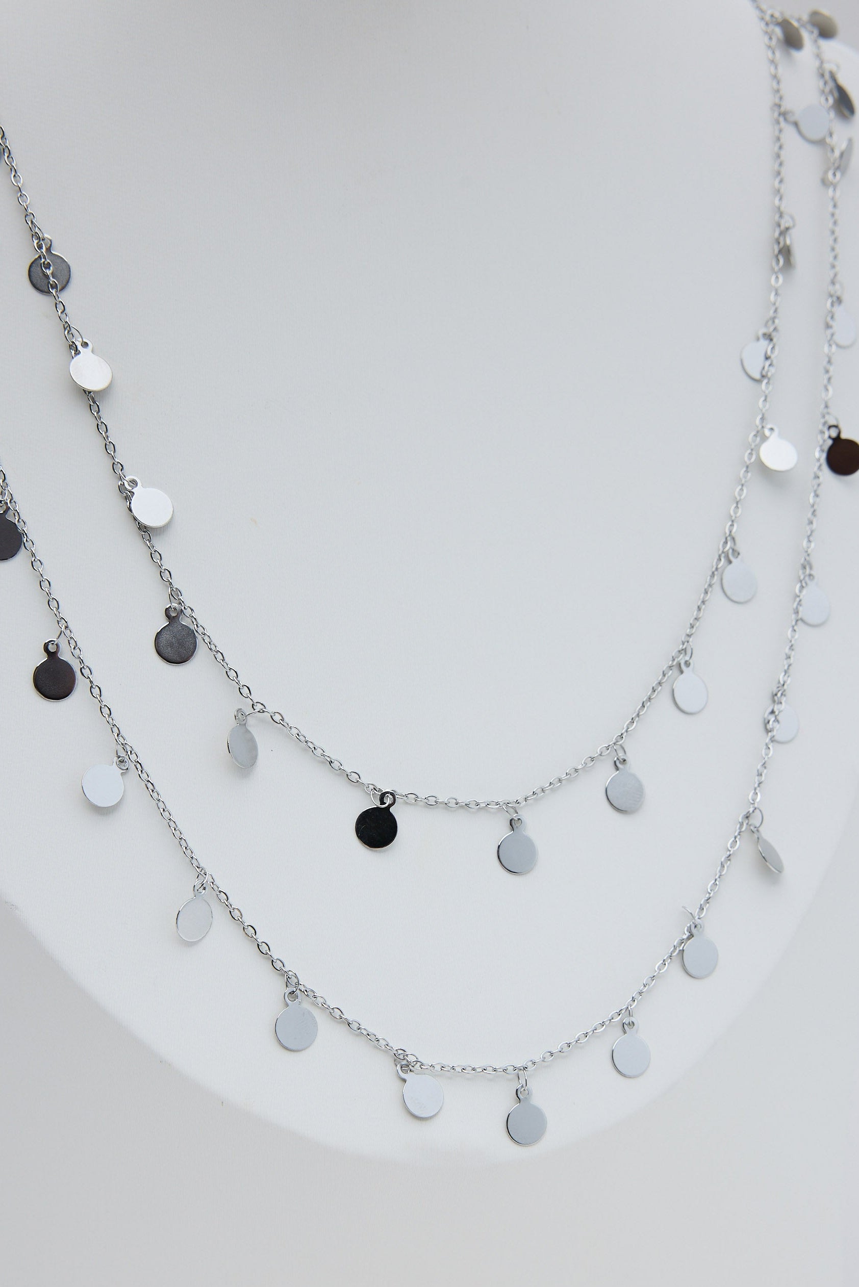 Layered silver necklace with black and white pendants on a white background