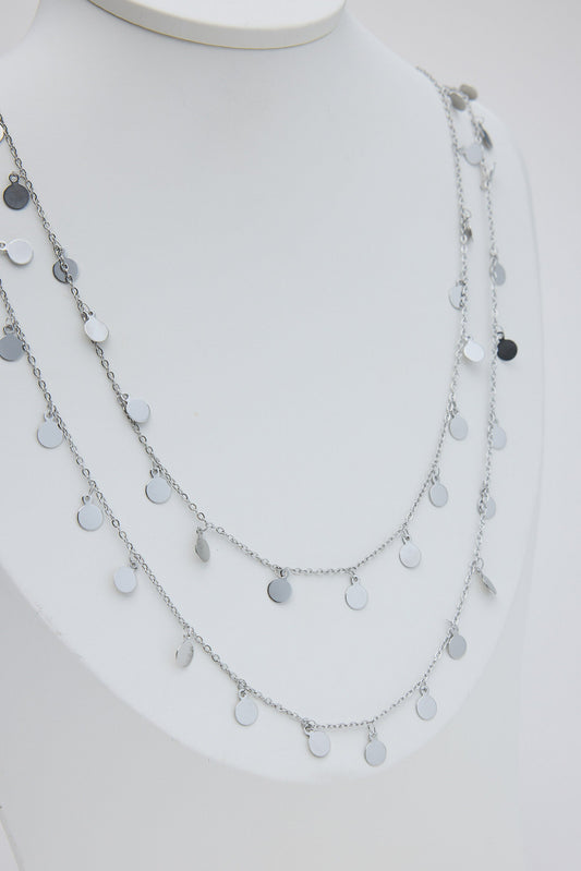 Layered silver necklace on a mannequin with a plain background