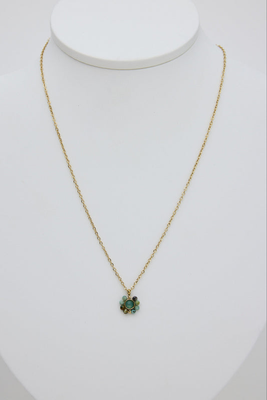 Gold necklace with a green pendant on a white mannequin bust