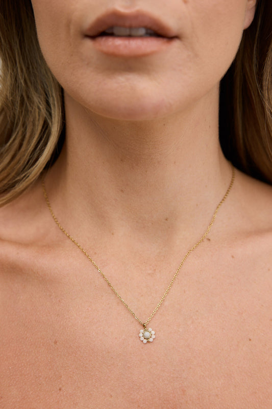 Close-up of a person wearing a delicate gold necklace with a small pendant.