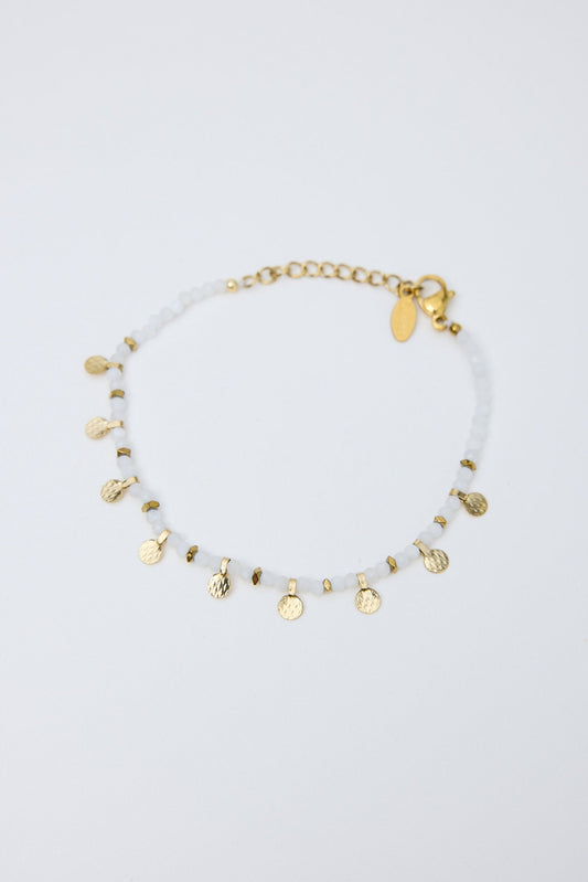 Gold bracelet with small charms on a light gray background