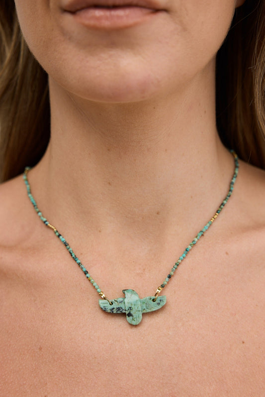 Necklace with a green pendant worn by a person against a neutral background