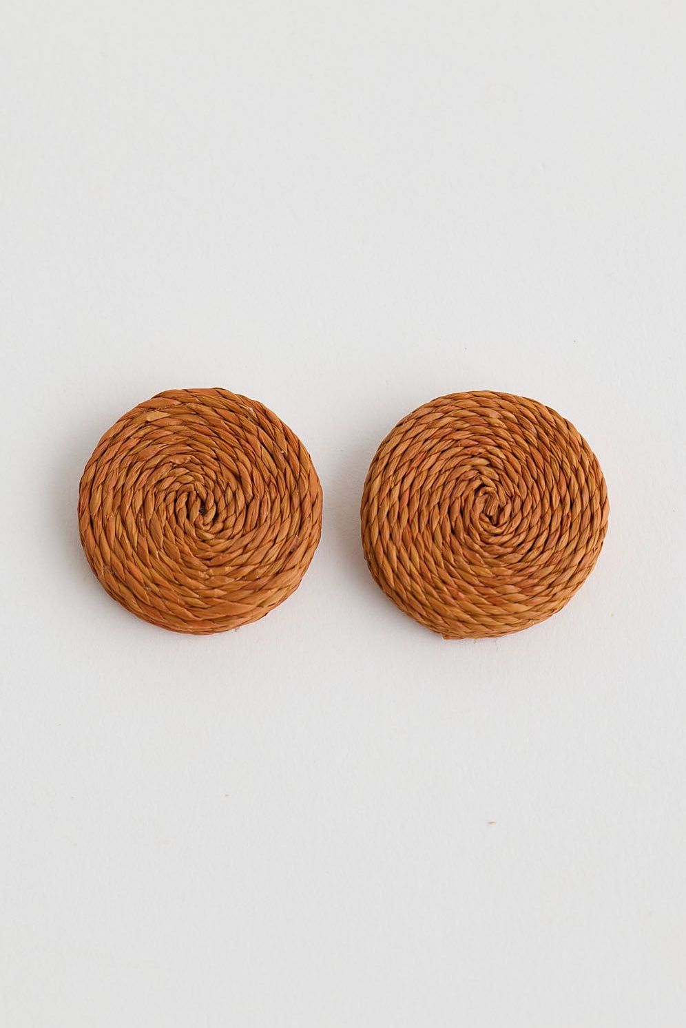 Pair of round brown earrings on a light gray background