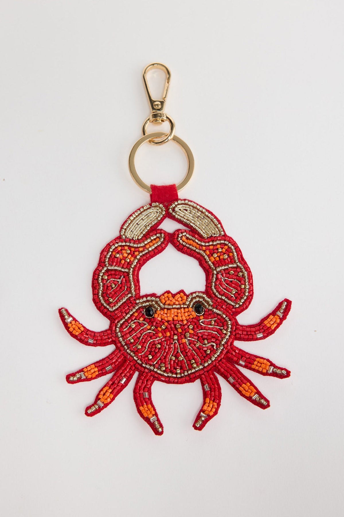 Large beaded crab keyring in bold red seed beads with orange accent claws, gold-tone bugle bead legs and black bead eyes, attached to a gold-tone clasp and split ring via a red leather tab, shown on a white background