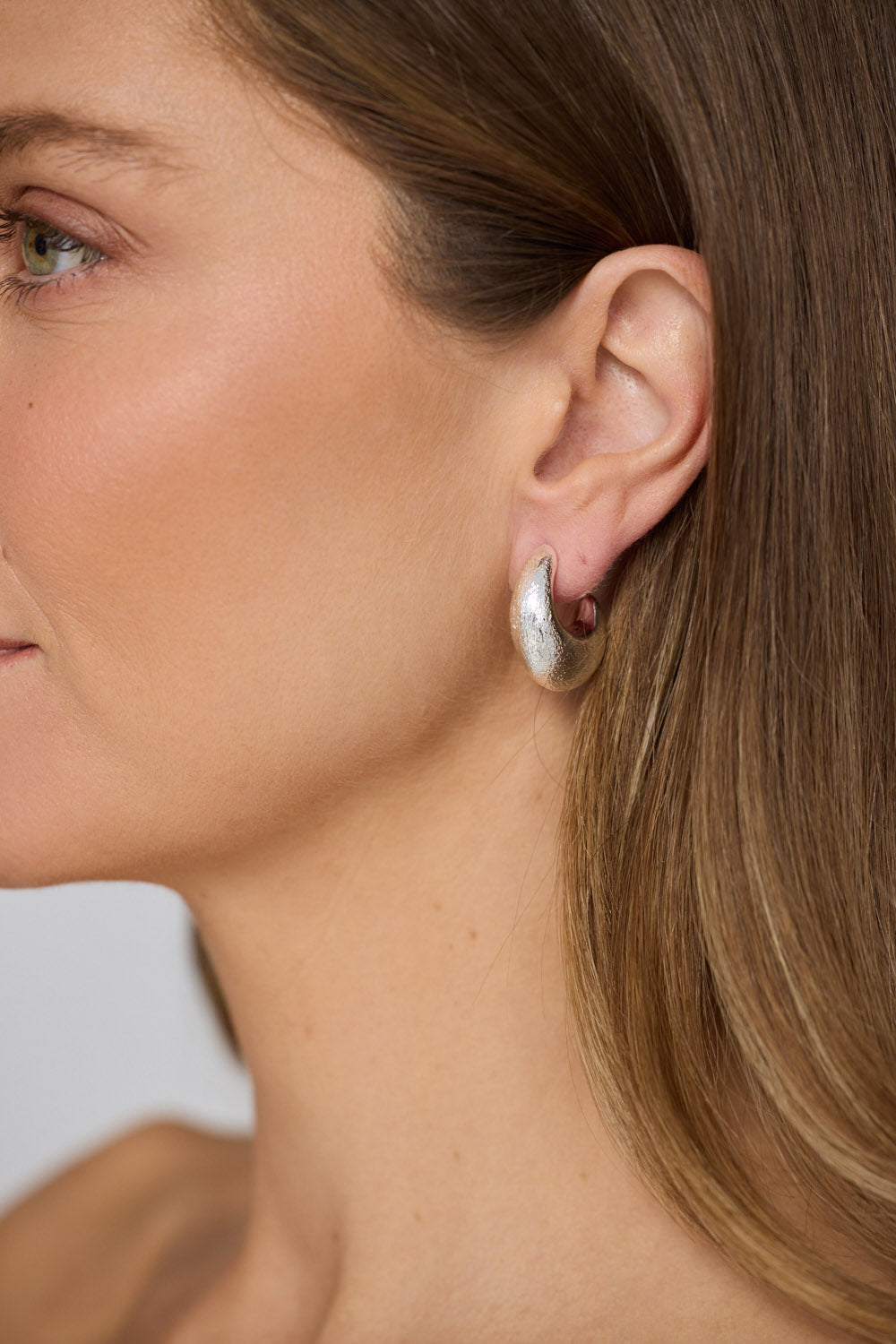 Model wearing Grace Earrings in silver with a textured finish, model close-up view on neutral background