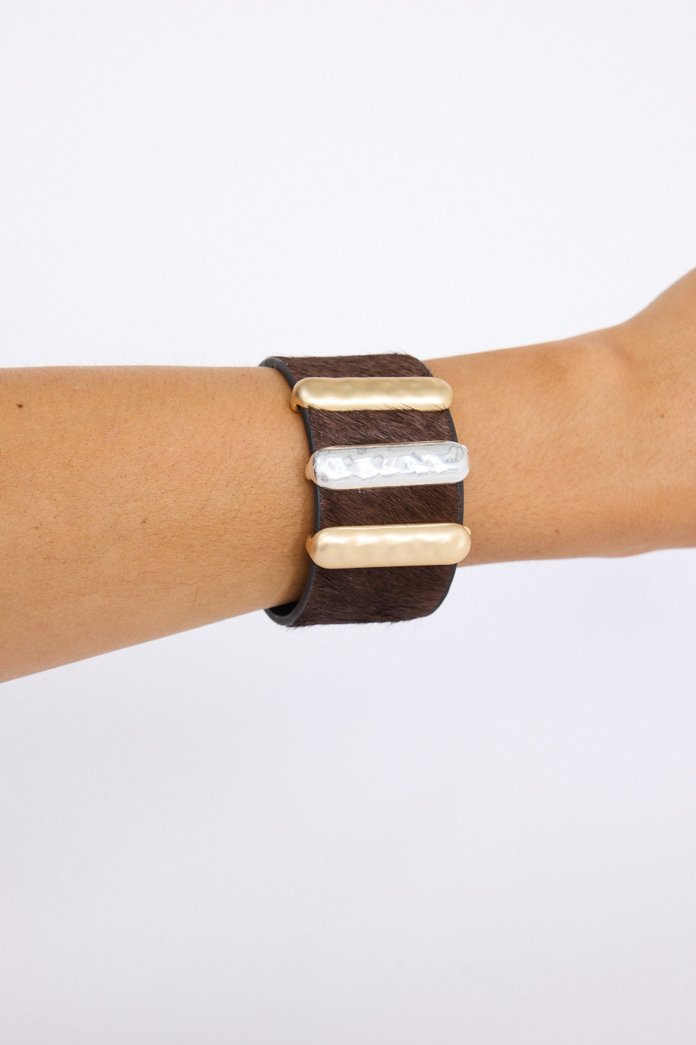 Model wearing Anima Cuff in tan with bold metal bar detailing, angled on-wrist view on neutral background